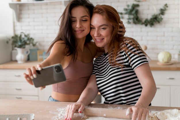 Casal de lésbicas tirando uma selfie na cozinha