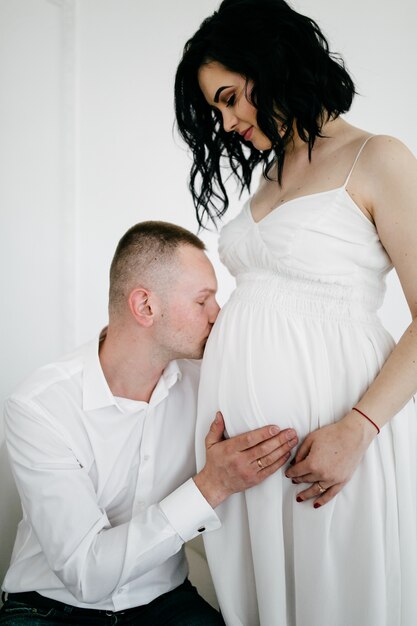 Casal de marido bonito e mulher muito pragnant posando no estúdio