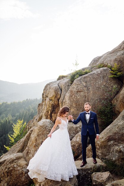 Casal de noivos românticos e apaixonados caminha pelas montanhas e pela floresta