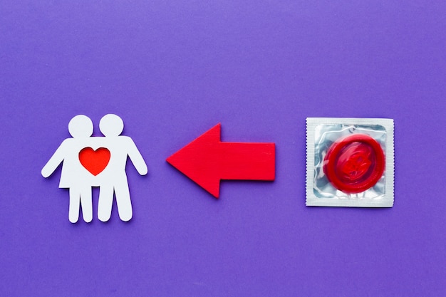 Foto grátis casal de papel ao lado do preservativo vermelho