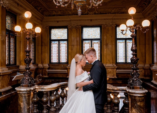 Casal de recém-casados abraçando no salão de luxo do castelo