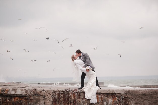 casal de recém-casados ​​se beijando no mar