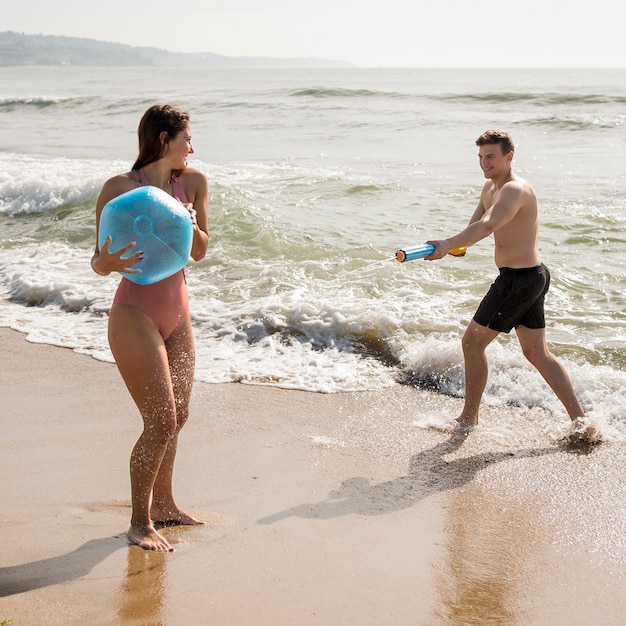 Casal de tiro completo brincando na praia