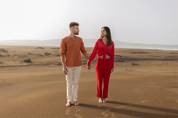 Casal de tiro completo de mãos dadas no deserto