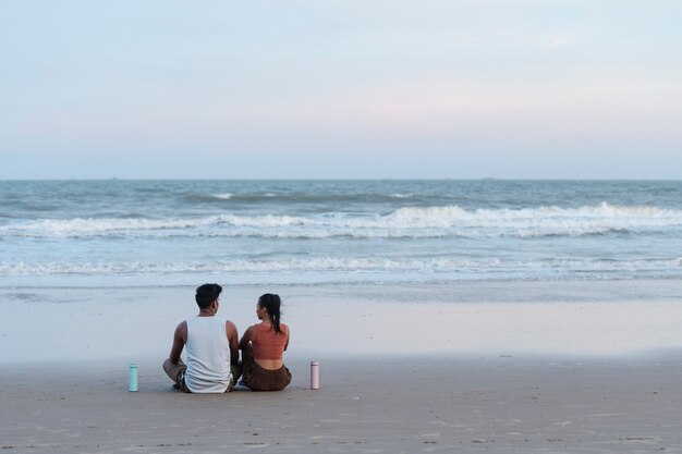 Casal de tiro completo meditando à beira-mar