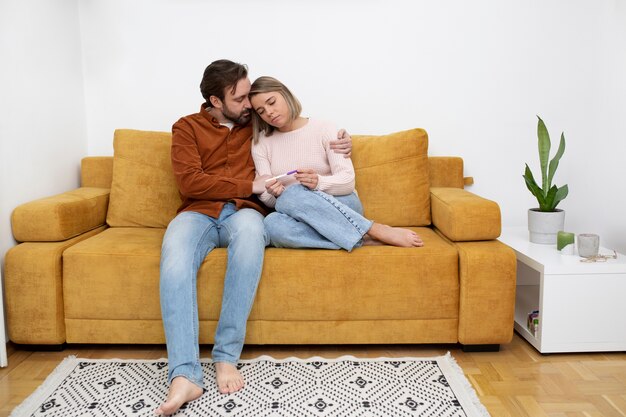 Casal de tiro completo sentado no sofá