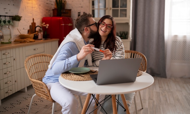 Foto grátis casal de tiro médio anunciando gravidez com laptop