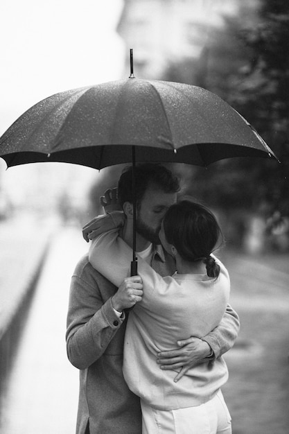 Casal de tiro médio beijando na chuva