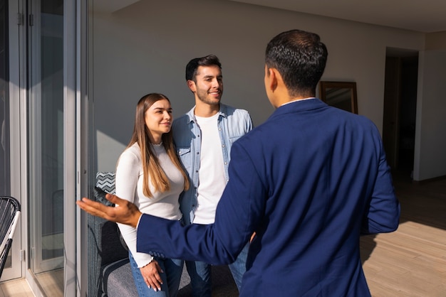 Casal de tiro médio conversando com agente imobiliário