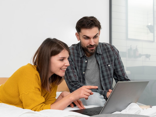 Casal de tiro médio olhando para um laptop