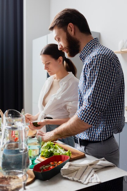 Casal de tiro médio preparando comida em casa