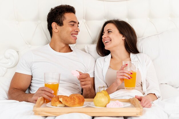 Casal de tiro médio tomando café da manhã na cama