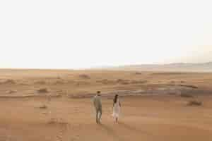 Foto grátis casal de tiro no escuro andando no deserto