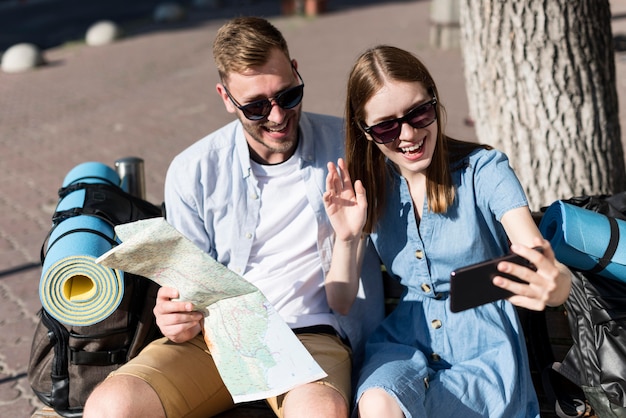 Casal de turista tomando uma selfie com mapa