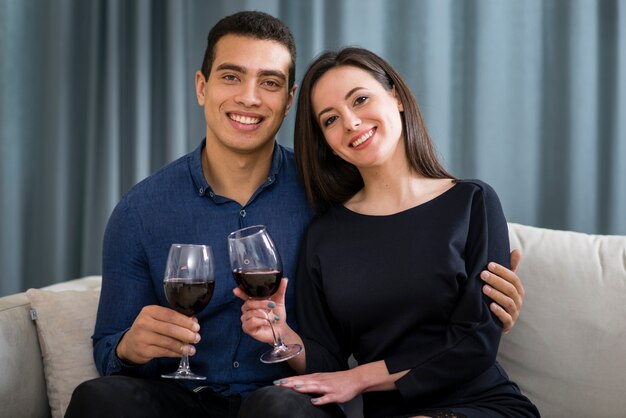Casal de vista frontal tomando uma taça de vinho enquanto está sentado no sofá