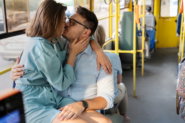 Casal de vista lateral beijando no transporte público