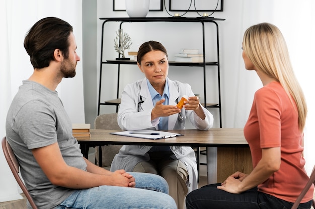 Casal de vista lateral conversando com o médico