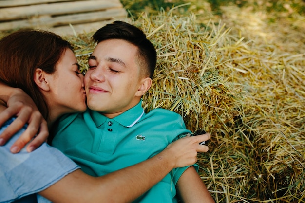 Casal deitado no palheiro beijando abraços