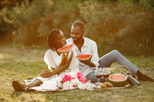 Casal despreocupado e relaxado, aproveitando o piquenique juntos. eles estão comendo melancia.
