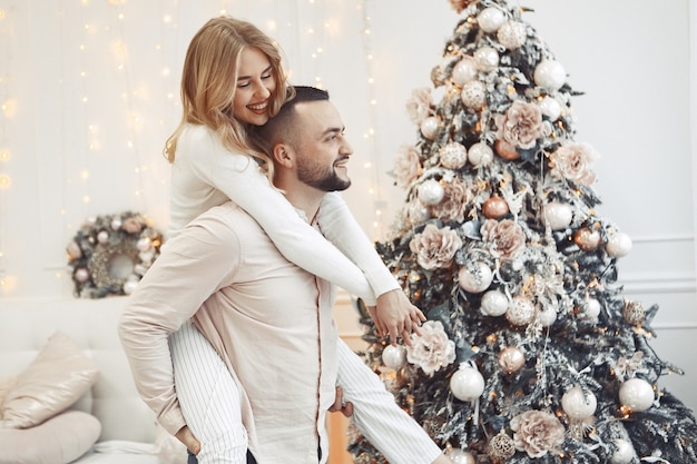 Casal elegante em casa perto da árvore de natal