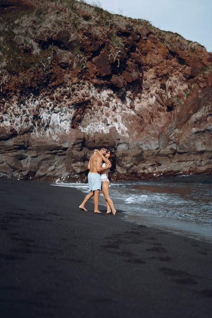 Casal elegante na praia perto de pedras