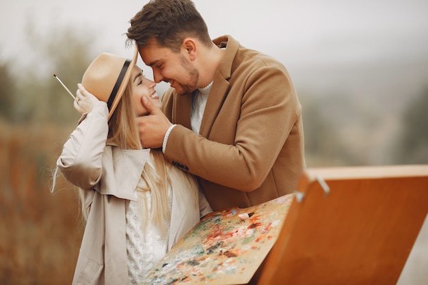 Casal elegante pintura em um campo de outono