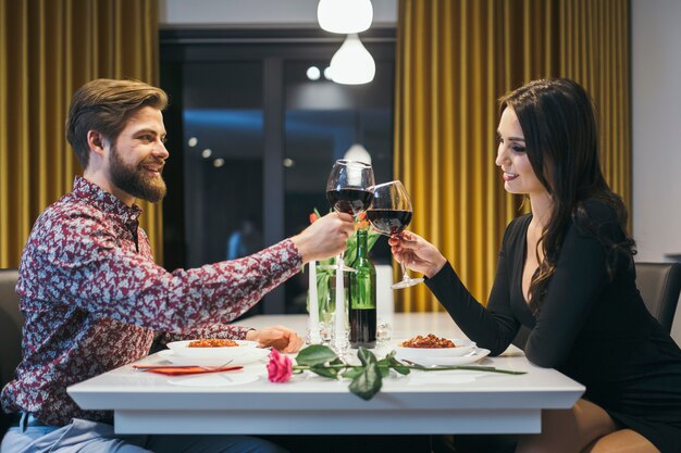 Casal elegante que choca com óculos que jantam