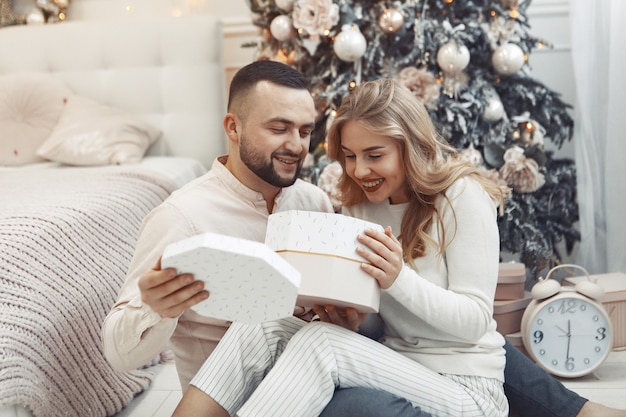 Casal elegante sentado em casa perto da árvore de natal