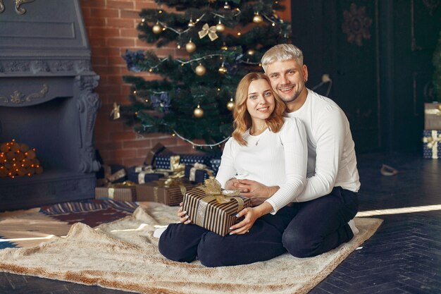 Casal elegante sentado em casa perto da árvore de natal