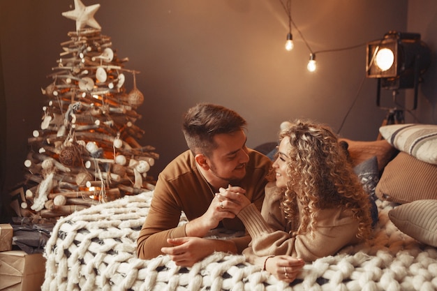 Casal elegante sentado em casa perto da árvore de natal