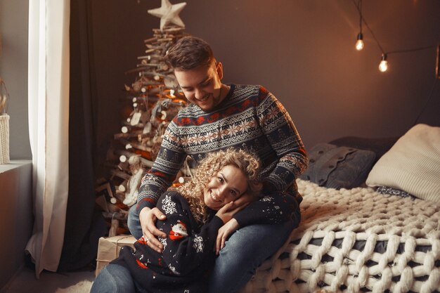 Casal elegante sentado em casa perto da árvore de natal