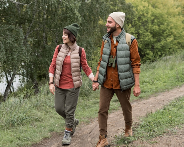 Casal em cena completa caminhando em uma trilha na natureza