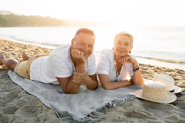 Casal em cena completa deitado na toalha na praia