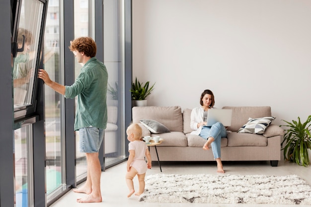 Casal em foto completa com bebê na sala de estar