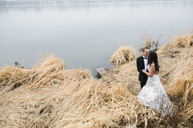 Casal em roupas de casamento à beira do lago