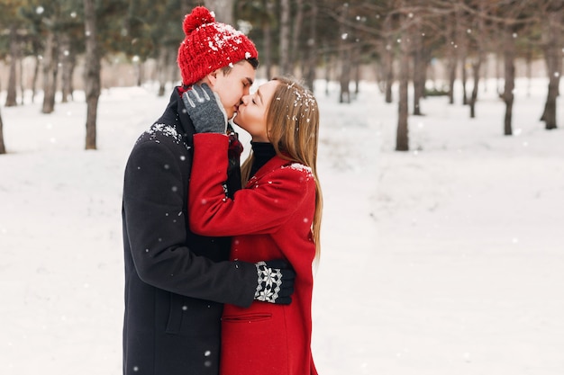 Casal em roupas de inverno, abraçando em um dia nevado