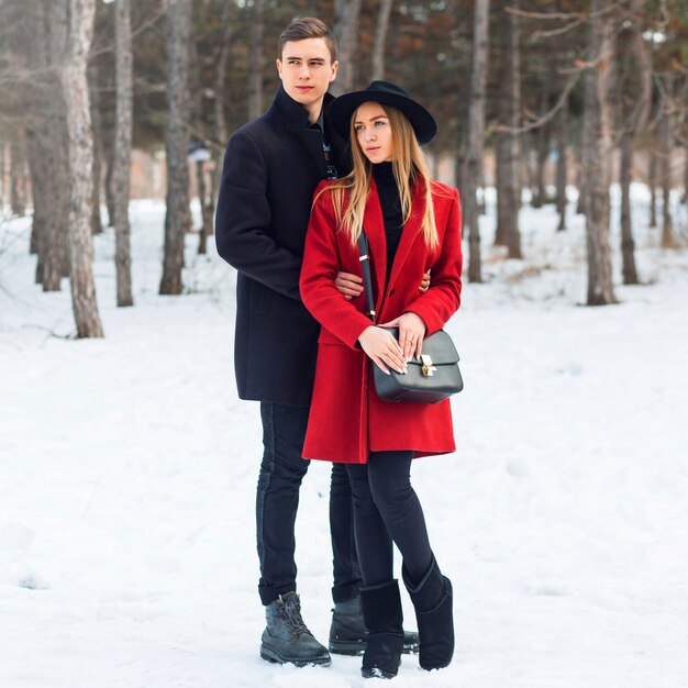 Casal em roupas de inverno, abraçando em um dia nevado