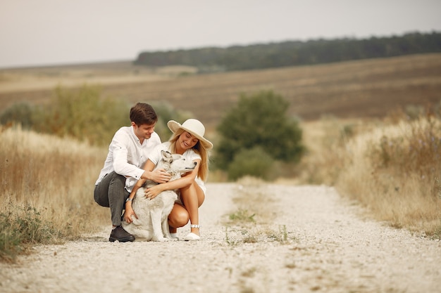 Casal em um campo de outono brincando com um cachorro