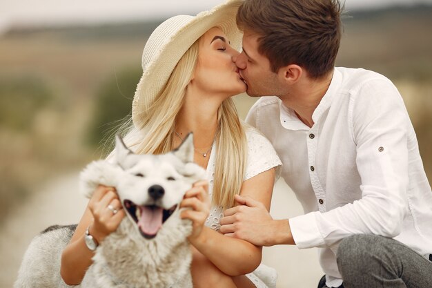 Casal em um campo de outono brincando com um cachorro