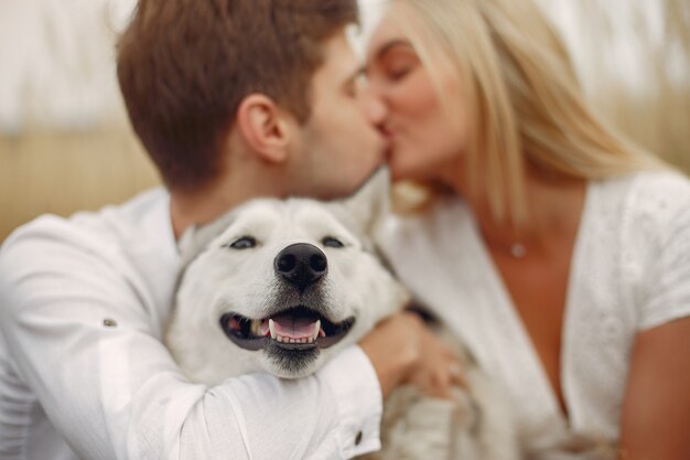 Casal em um campo de outono brincando com um cachorro