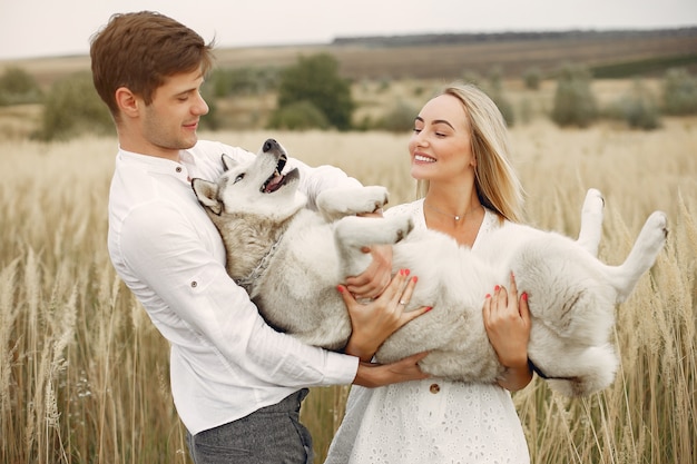 Casal em um campo de outono brincando com um cachorro