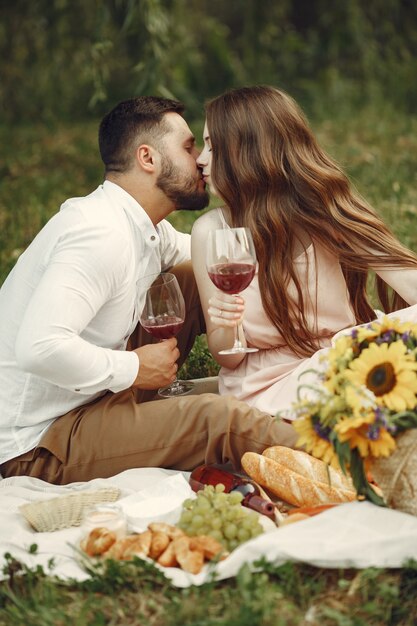 Casal em um campo. Morena em um vestido branco. Pares sentados na grama.