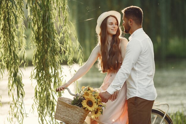 Casal em um parque de verão. Pessoas com bicicletas vintage. Menina com um chapéu.