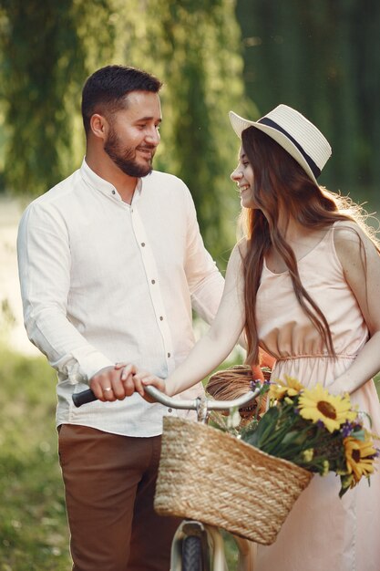 Casal em um parque de verão. Pessoas com bicicletas vintage. Menina com um chapéu.