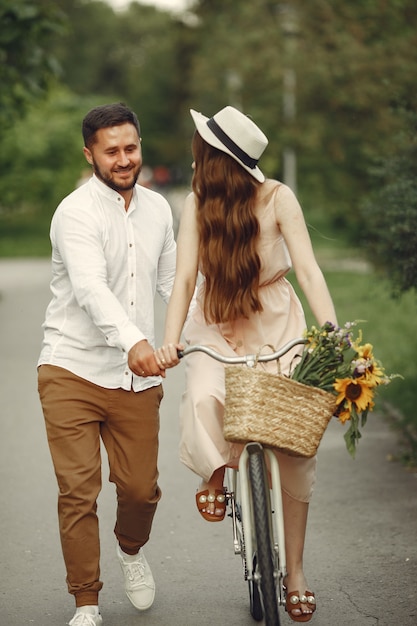 Casal em um parque de verão. Pessoas com bicicletas vintage. Menina com um chapéu.