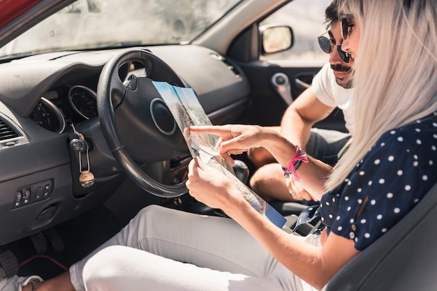 Casal em viagem de férias sentado dentro do carro olhando mapa