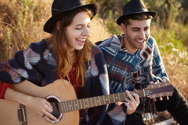 Casal estiloso com guitarra no campo