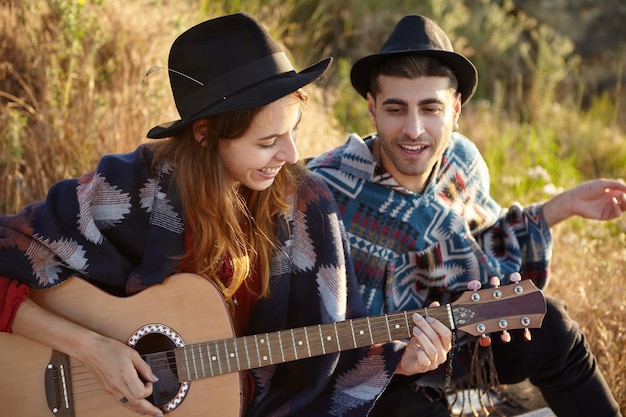 Foto grátis casal estiloso com guitarra no campo