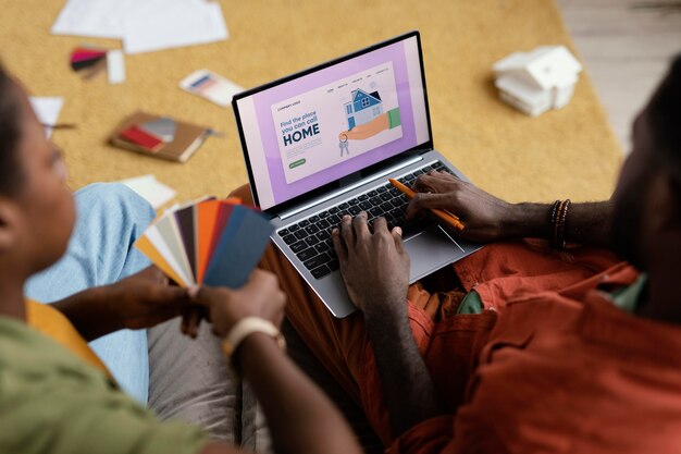 Casal fazendo planos para reformar a casa usando paleta de cores e laptop