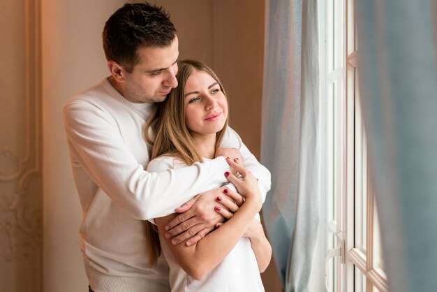 Casal feliz abraçado e olhando pela janela